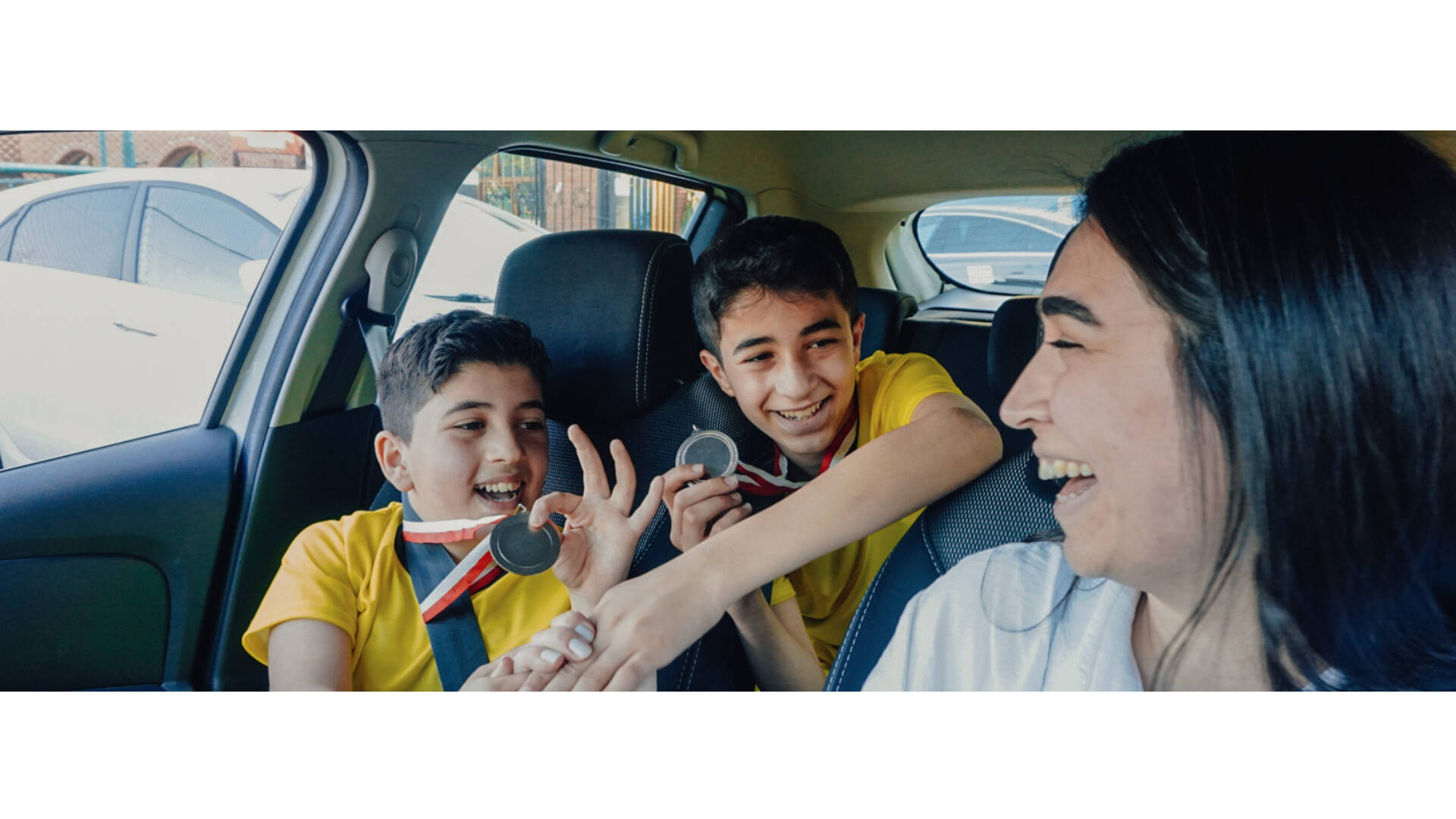 A parent and two children in the car after a sporting game.